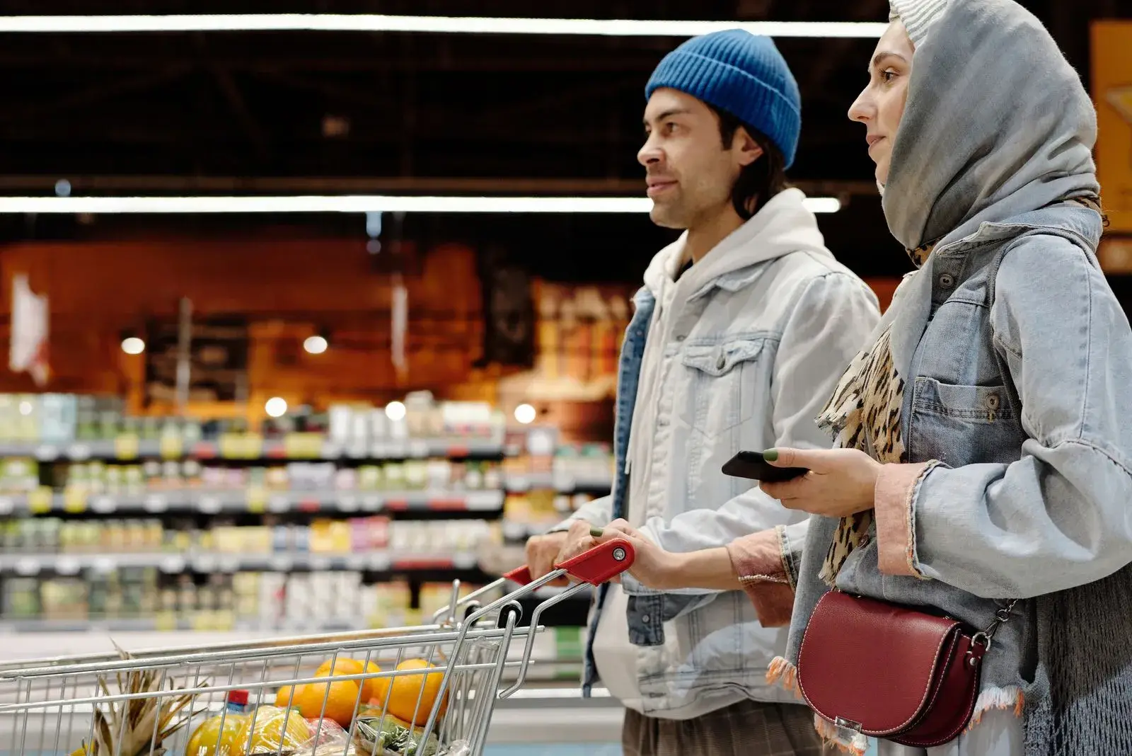 A couple with a shopping cart in a supermarket aisle
