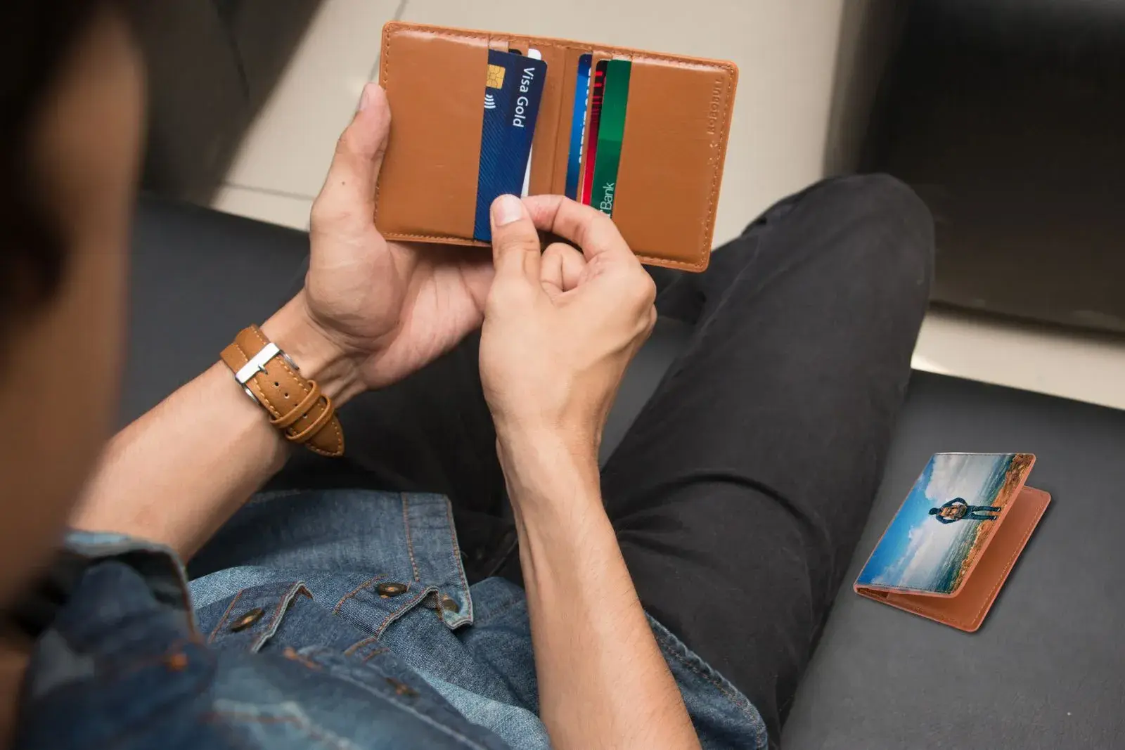 A person holding an open leather wallet with several cards