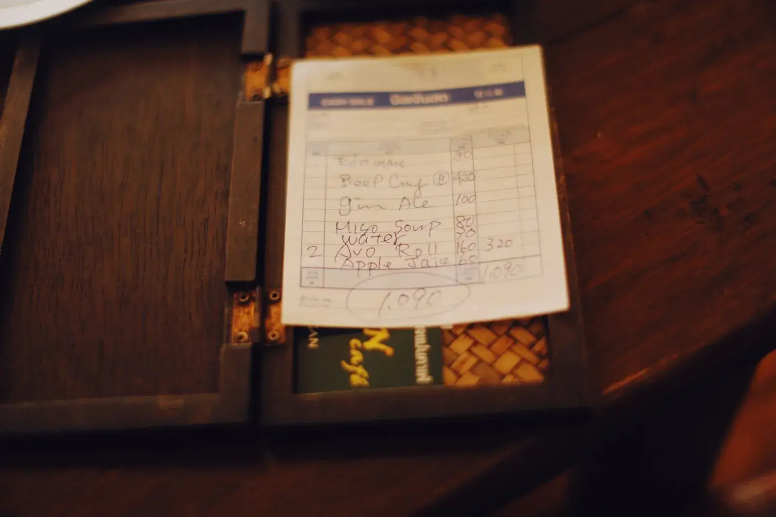 A restaurant bill in an open check presenter on a wooden table