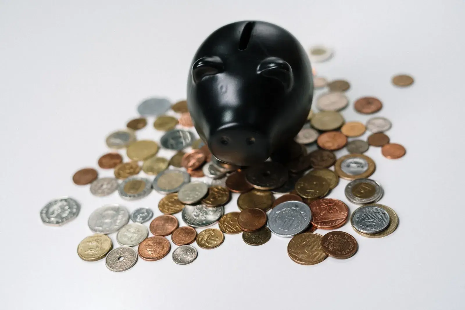 A black piggy bank surrounded by scattered coins